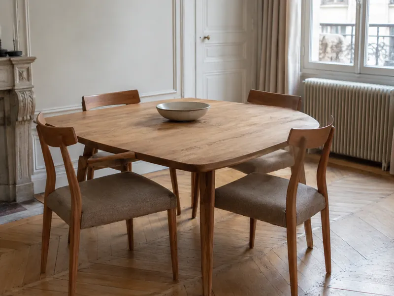 Quatre chaises en chêne à assise en tissu taupe autour d'une table de salle à manger